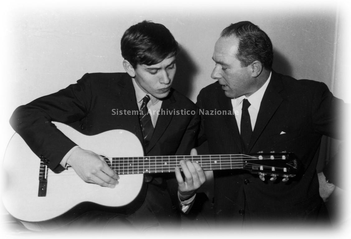   Oliviero Pigini con Gianni Morandi che imbraccia una chitarra Eko, 1965 ca. (Tecnostampa, fondo Oliviero Pigini).
